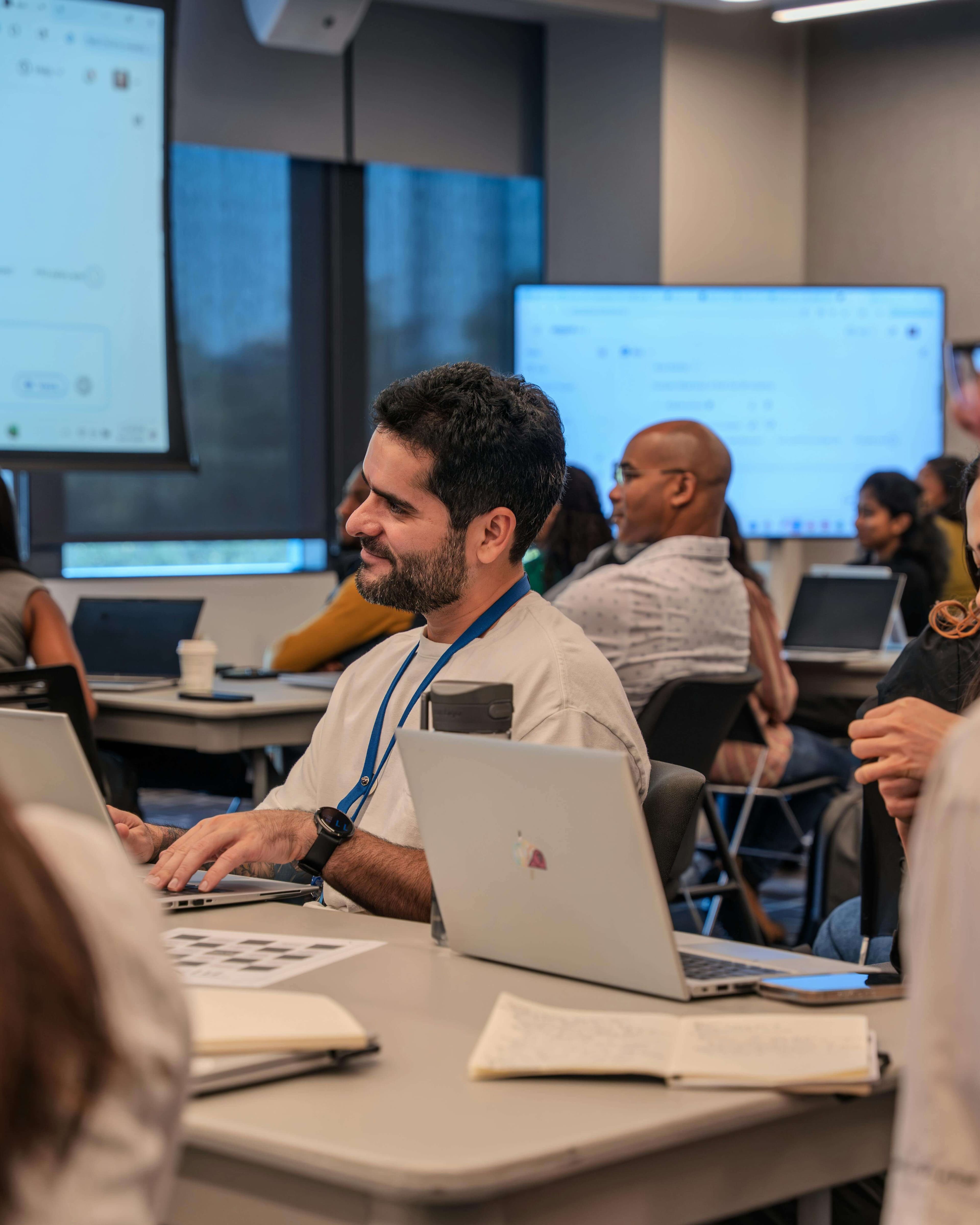 A smiling engineer collaborating at a laptop with diverse teammates in the background — the kind of people we build software with.